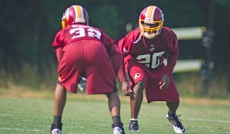 Washington Redskins safety Oshiomogho (20) runs through drills against Anderson Russell (32) during the first day of training camp at Redskins Park in Ashburn, Va., Friday, July 29, 2011. (Rod Lamkey Jr./The Washington Times)