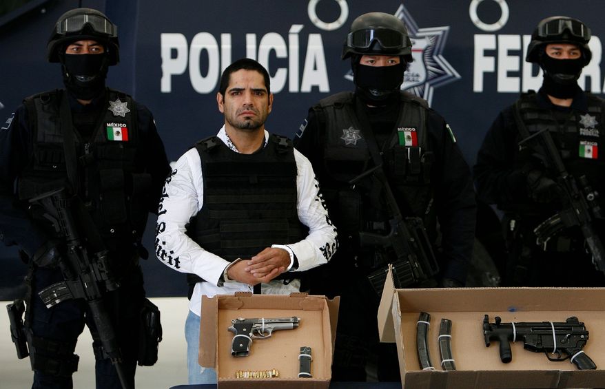 ** FILE ** Jose Antonio Acosta Hernandez gets the customary Mexican "perp walk" by federal police officers in Mexico City after his arrest. Mr. Acosta, a former federal police officer, was one of Mexico's most-wanted. (Associated Press)