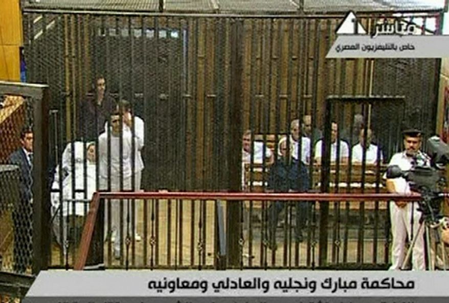 Ousted Egyptian President Hosni Mubarak lies on a hospital gurney (left) inside a cage in a courtroom in Cairo as other defendants sit on the right. Mr. Mubarak, his two sons and seven other defendants are charged with "premeditated murder" of hundreds of protesters. (Egyptian State Television via Associated Press)