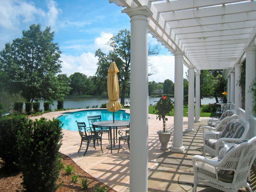 The in-ground swimming pool is surrounded with new decking. Seating is provided under a nearby pergola.