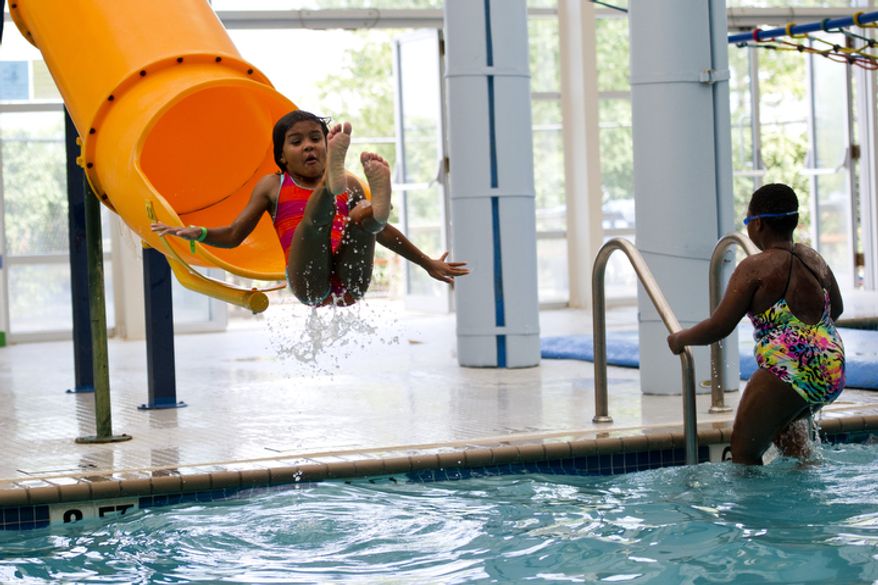 Talia Jackson, 6, of the District, gets some air as she shoots out of the water slide at the Rollingcrest-Chillum Splash Pool, in Hyattsville on Monday. (Drew Angerer/The Washington Times)