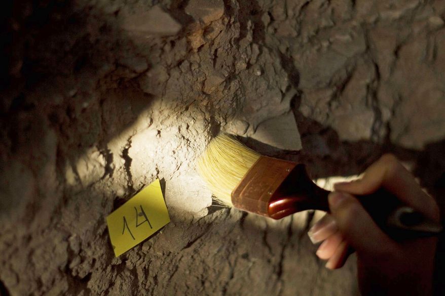 An Israeli archaeologist carefully cleans a part of a wall at the site, where buildings date from the 10th or 9th century B.C.