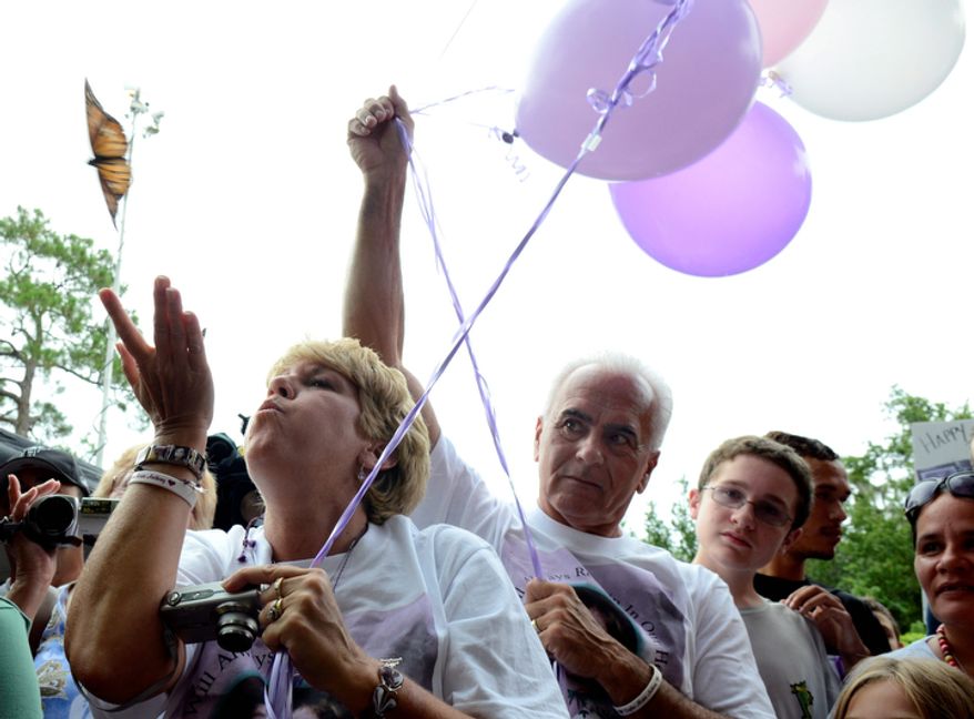 Cindy Anthony, left, blows a butterfly off her hand as George Anthony, center, watches, during a butterfly and balloon release as part of a memorial ceremony at the site where the body of their granddaughter Caylee Anthony was found on what would have been her sixth birthday in Orlando, Fla., Tuesday, Aug. 9, 2011. Their daughter Casey Anthony was acquitted of the most serious charges related to the death of her daughter Caylee Anthony. (AP Photo/Phelan M. Ebenhack)