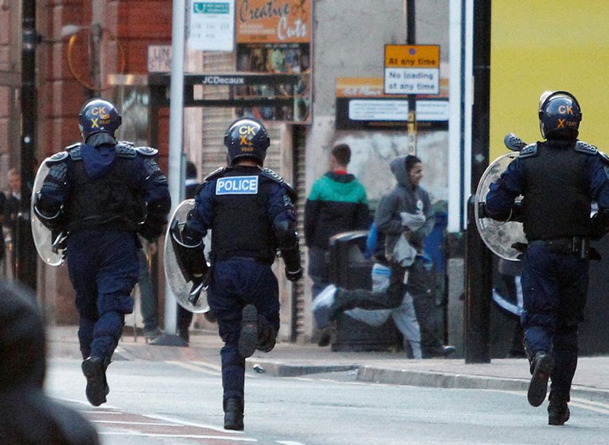 Riot police chase alleged looters during civil disturbances in Manchester, England. Three nights of looting and burning by crowds of young people appears to have spread from the capital to other locations in Britain. (AP Photo/Jon Super).