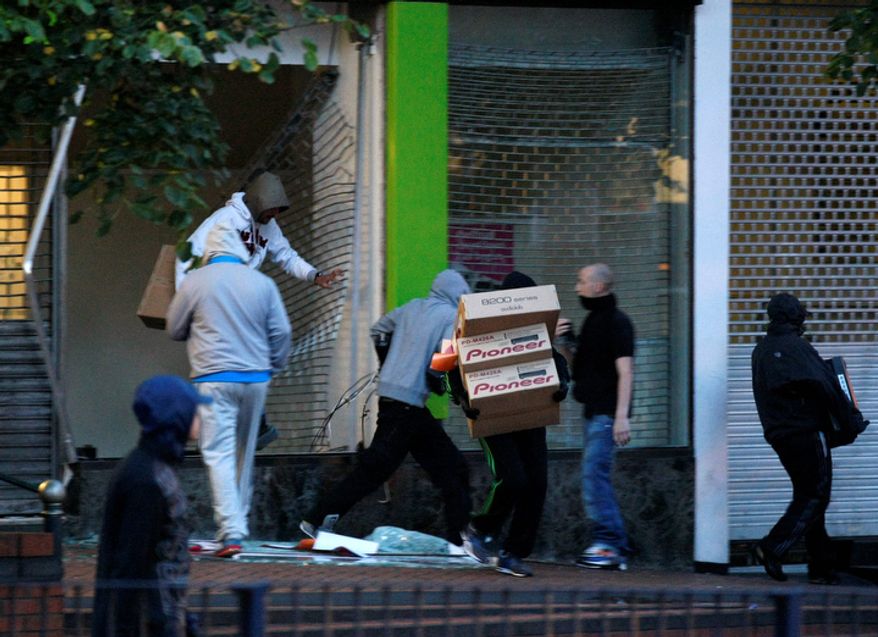 Looters take electrical goods after breaking into a store during the second night of civil disturbances in central Birmingham, England. (AP Photo/Tim Hales)