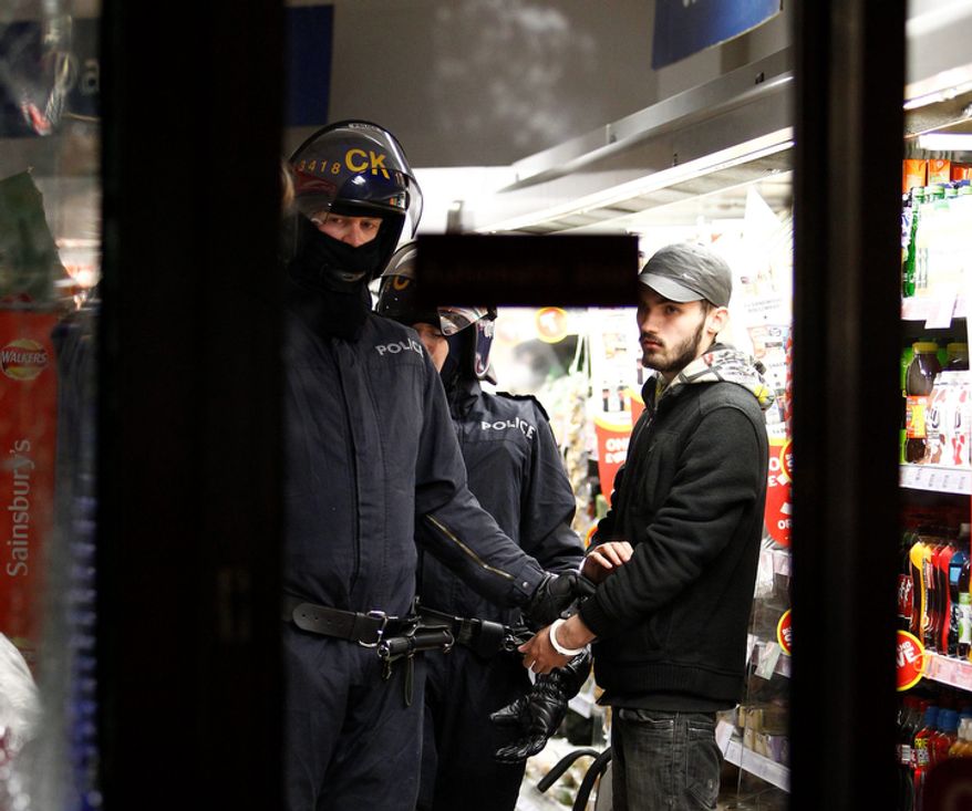 A riot policeman holds a looter in a Sainsbury's supermarket on Deansgate during civil disturbances in Manchester, England. (AP Photo/Jon Super).