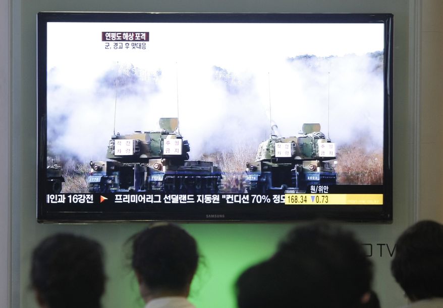 South Koreans at Seoul's main railroad station watch a TV news program on Wednesday, Aug. 10, 2011, showing file video footage of South Korean army K-9 self-propelled howitzers during a previous military exercise. The South's marines returned fire Wednesday after North Korea launched artillery shells into waters near the disputed maritime line that separates the two rivals, South Korean defense officials said. (AP Photo/Ahn Young-joon)