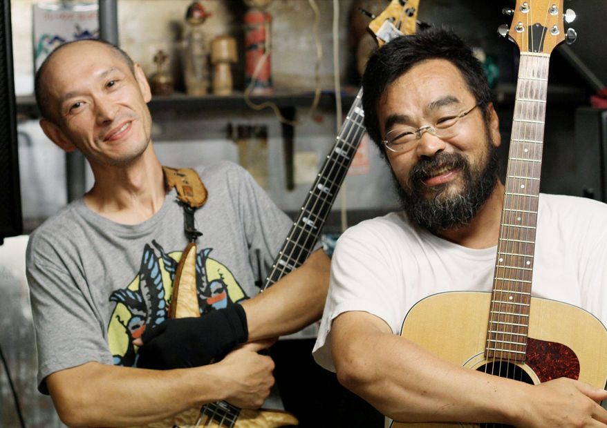 The tsunami disaster and economic hardship in Japan have created a new breed of entrepreneurs. Kenji Yui (left) and Hideki Suenaga have opened a makeshift "temporary pub" in Ishinomaki where they sell sake and cheap clothing, and play classic rock covers for diehard locals who refuse to abandon the devastated business district. (Christopher Johnson/Special to The Washington Times)