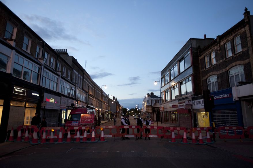 Police stand guard Aug. 11, 2011, as they block access to the high street in Tottenham, north London. (Associated Press)