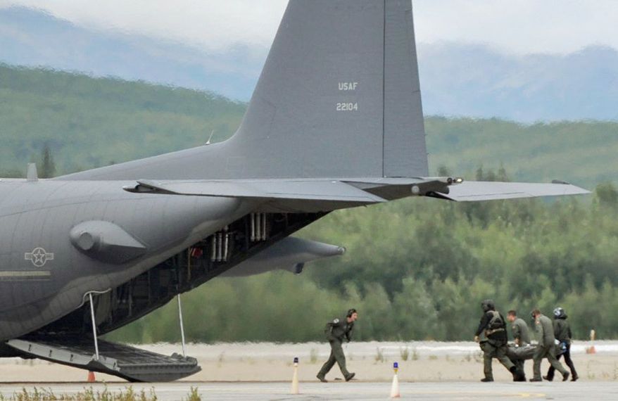 Rescuers from the Alaska Air National Guard carry one of the victims of a small-plane crash to a waiting HC-130 at McGrath Airport in Kuskokwim, Alaska, on Sunday. The pilot and one passenger were killed; a couple and their two children survived. (Anchorage Daily News via The Associated Press)