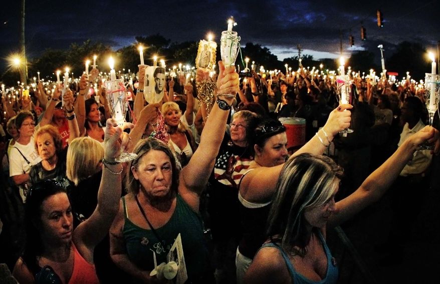 Fans of Elvis Presley from all over the world gather at the gates of his Graceland mansion for a candlelight vigil on Monday, Aug. 15, 2011, in Memphis, Tenn., to mark the 34th anniversary of his death. (AP Photo/Memphis Commercial Appeal, Jim Weber)