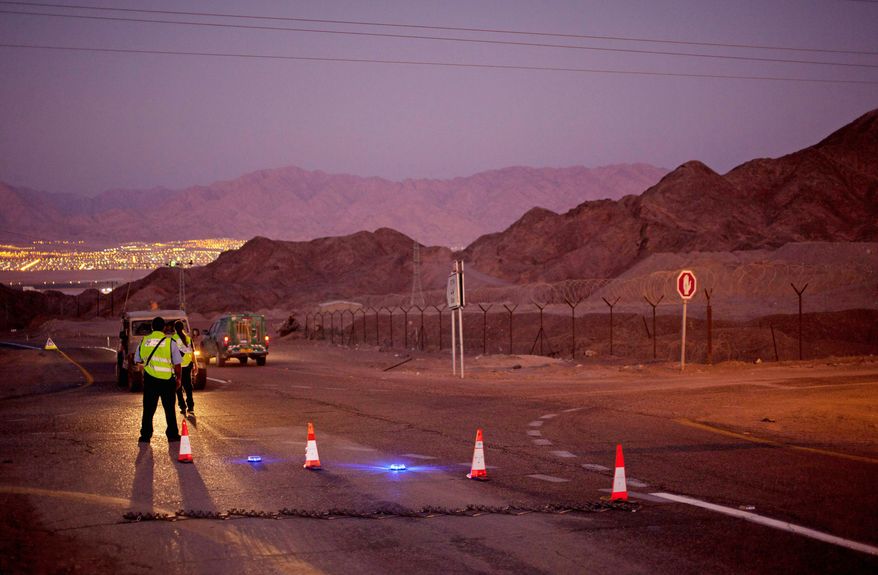 Police officers stop the traffic on a road in the Arava Desert leading to the southern Israeli town of Eilat on Thursday after gunmen crossed from the neighboring Egyptian Sinai Peninsula. They killed six Israelis and wounded at least a dozen in a string of attacks. (Associated Press)