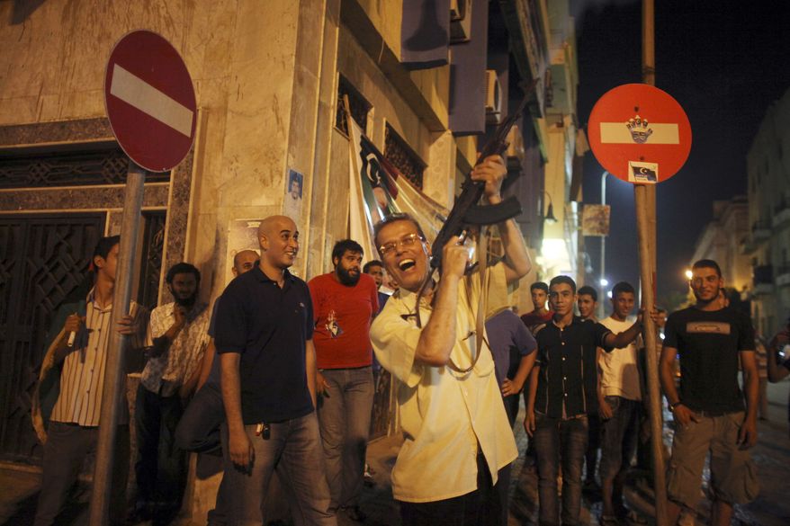 A man shoots to the sky as he celebrates the capture in Tripoli of Moammar Gadhafi's son and one-time heir apparent, Seif al-Islam, at the rebel-held town of Benghazi, Libya, early Monday, Aug. 22, 2011. Libyan rebels raced into Tripoli in a lightning advance Sunday that met little resistance as Moammar Gadhafi's defenders melted away and his 40-year rule appeared to rapidly crumble. The euphoric fighters celebrated with residents of the capital in the city's main square, the symbolic heart of the regime. (AP Photo/Alexandre Meneghini)