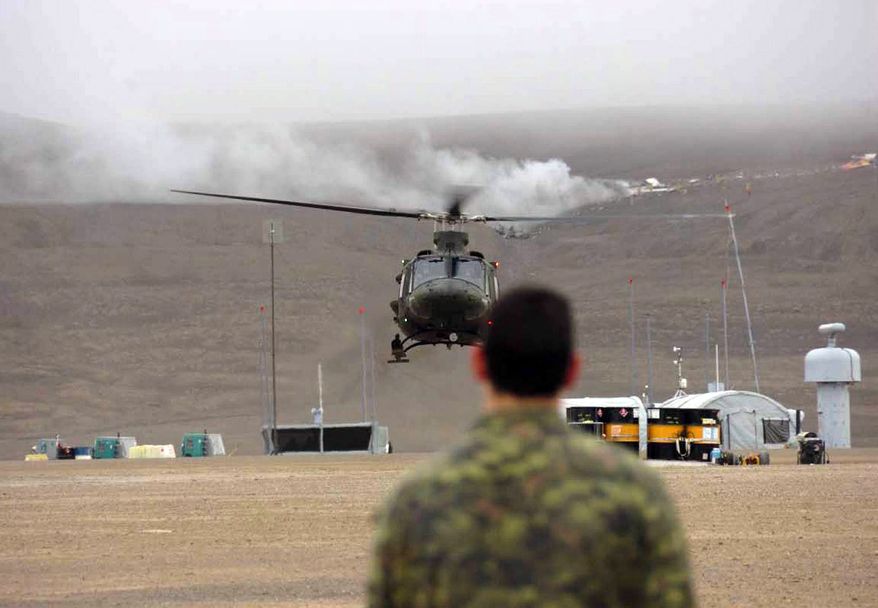 A member of the Canadian Forces watches a helicopter in front of the wreckage of a chartered Boeing 737-200 aircraft that crashed into the hill behind on Saturday, Aug. 20, 2011, in Resolute Bay in Canada's Nunavut territory. (AP Photo/Department of National Defense, Master Cpl. Randy Burnside)