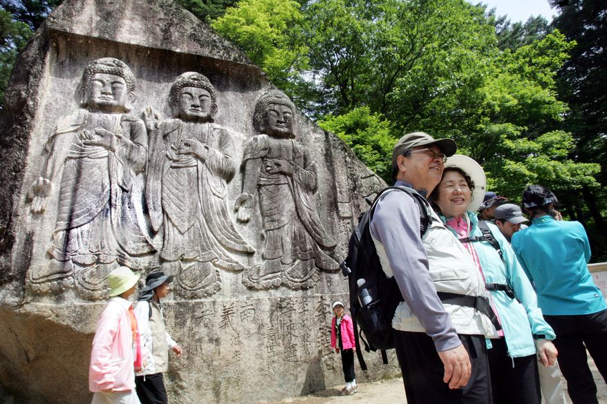 ** FILE ** South Korean tourists pose in front of the Sambulam, the three Buddha sculpture, on Diamond Mountain in June 2007. (AP Photo/Ahn Young-joon, File)