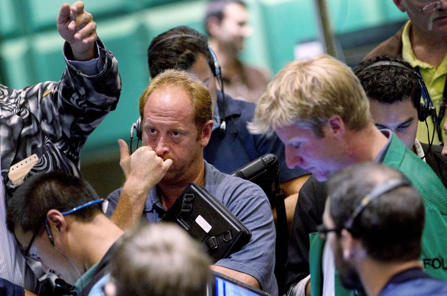 associated press
Traders work in the gold and silver options pit at the New York Mercantile Exchange in New York on Wednesday, watching as gold prices plunged 5.6 percent. Increasing orders for U.S. durable goods eroded demand for the metal - which closed at $1,757 per ounce - as a haven asset.
