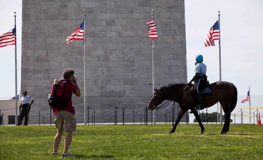 Dave Southward of Hamilton, Ontario, takes photos of the Washington Monument in D.C., behind a temporary barrier set up by the U.S. Park Police on Aug. 24, 2011. The monument will be closed for an indefinite period of time while the National Park Service inspects it for damage resulting from the 5.8-magnitude earthquake that hit the East Coast on Aug 23, 2011. (Pratik Shah/The Washington Times)