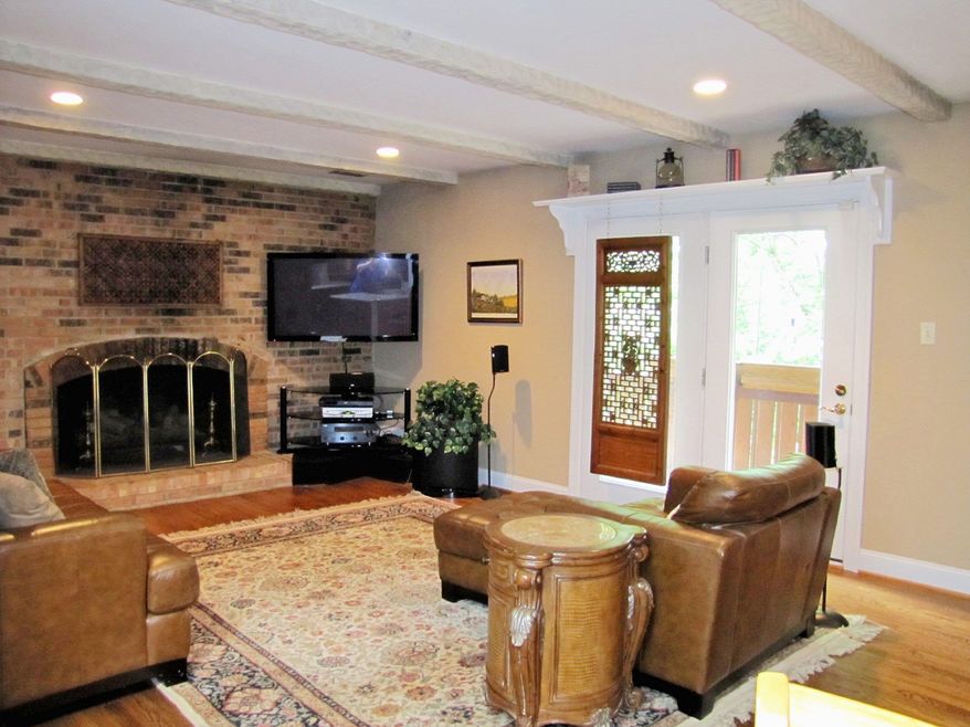 The family room has a beamed ceiling, an oversized gas fireplace and French doors that open onto the deck.