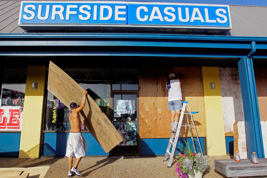 Kiel Murphy, left, helps his father, Bill Brightbill, place boards over windows at Surfside Casuals in Nags Head, N.C. Preparations for the arrival of Hurricane Irene are underway as mandatory evacuations are in order for Dare County. (AP Photo/Gerry Broome)
