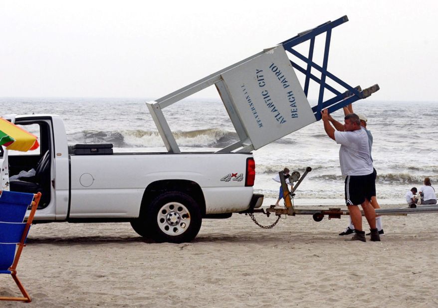 Atlantic City lifeguard, John Malecki, and Lt. John Ammerman put a lifeguard stand in a truck as they clear the beach in N.J. (AP Photo/The Press of Atlantic City, Danny Drake) MANDATORY CREDIT