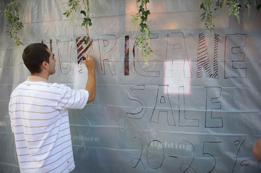 Boris Bulatovic an employee at Decorium on King Street in Old Town Alexandria, Va, Friday, August 26, 2011, writes a message on a sheet of protective plastic on the storefront. In a city which saw severe flooding during Hurricane Isabel in 2002, business owners and residents are wasting no time preparing for Hurricane Irene. (Rod Lamkey Jr./The Washington Times)