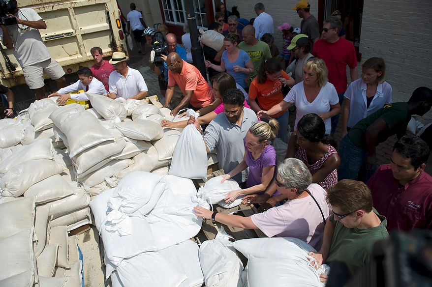 People grasp for sand bags from a city maintenance truck at the corner of King and N. Lee Streets in Old Town Alexandria, Va, Friday, August 26, 2011. In a city which saw severe flooding during Hurricane Isabel in 2002, business owners and residents are wasting no time preparing for Hurricane Irene. (Rod Lamkey Jr./The Washington Times)