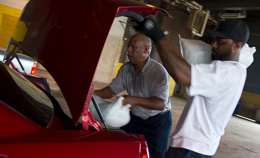 Jerry Stanback, left, a general foreman with the Department of Public Works, and Cameron Washington, a motor vehicle operator, load sandbags in. District residents waited in long lines at the Department of Public Works in Southeast Washington, D.C., on Friday, Aug. 26, 2011 to pick up sandbags in preparation for Hurricane Irene. Each District resident is entitled to five sandbags. The Department of Public Works says they have 75,000 bags today and more coming tomorrow. They'll be distributing sandbags until midnight Friday and will start again at 8 a.m. Saturday morning. (Barbara L. Salisbury/The Washington Times)