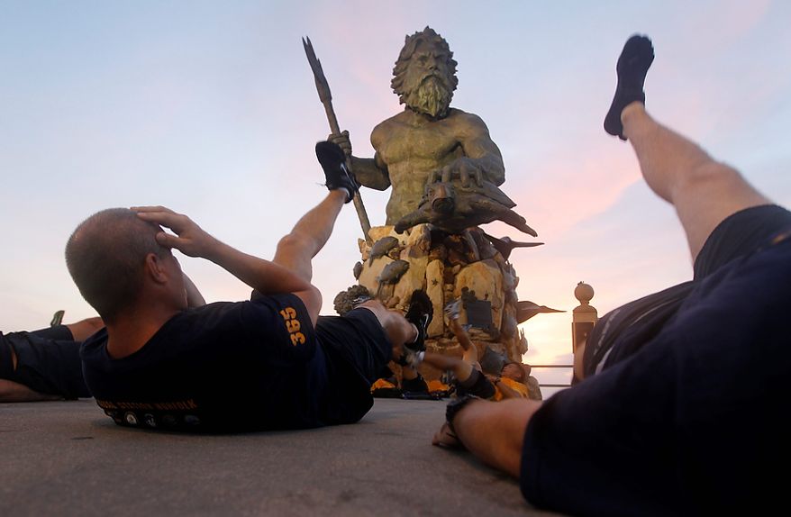US Navy Chief Petty Officers conduct physical training in front of a statue of Neptune on the oceanfront of Virginia Beach, Va., Friday, Aug. 26, 2011. Hurricane Irene is expected to hit the area Saturday. (AP Photo/Steve Helber)