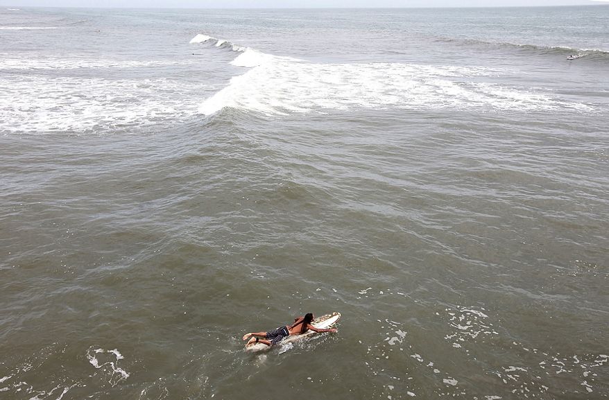 A surfer paddles out hoping to catch some big waves ahead of the arrival of Hurricane Irene in Nags Head, N.C., Friday, Aug. 26, 2011 on North Carolina's Outer Banks. (AP Photo/Charles Dharapak)