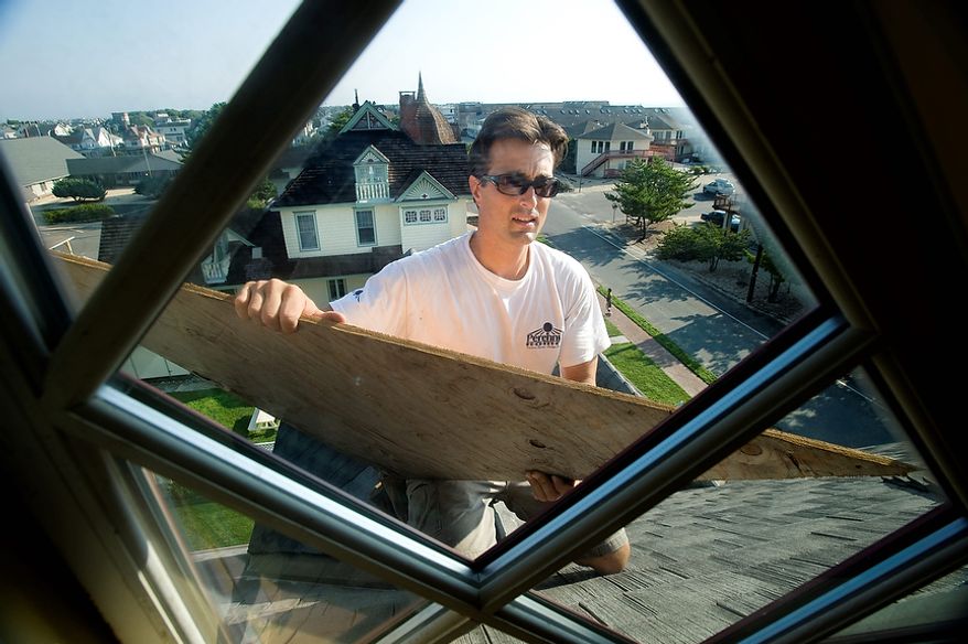 Jim Blahut of Perennial Homes boards up the windows at Williams Cottage Inn, as residents prepare for the arrival of Hurricane Irene makes it's way up the east coast, Friday Aug. 26, 2011 in Beach Haven, NJ. The building is circa 1886 and was renovated and opened as a bed and breakfast in 2007. (AP Photo/Joe Epstein)