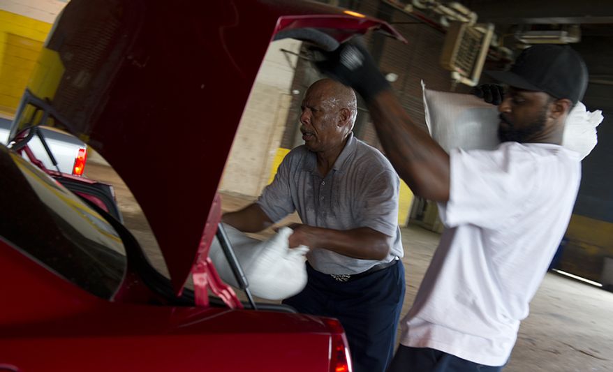 Jerry Stanback (left), a general foreman with D.C.'s Department of Public Works, and Cameron Washington, a motor vehicle operator for the department, load sandbags into the trunk of a city resident's vehicle at the department headquarters in southeast Washington on Aug. 26, 2011, a day before Hurricane Irene was expected to hit the D.C. region. (Barbara L. Salisbury/The Washington Times)