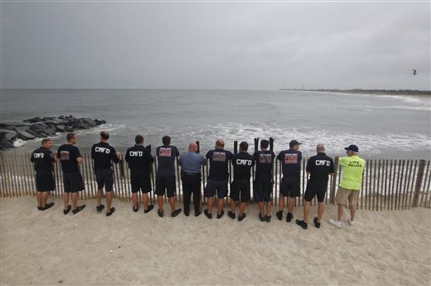 Members of Cape May Fire Department look look out at a stormy Atlantic early Saturday, Aug. 27, 2011, in Cape May, N.J. , as Hurricane Irene approaches. Hurricane-force winds and drenching rains from Irene battered the North Carolina coast early Saturday as the storm began its potentially catastrophic run up the Eastern Seaboard. (AP Photo/Mel Evans)