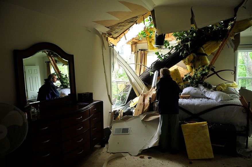 Mindy Prager looks at the damage from an uprooted tree that crashed into the bedroom of Debbie Martinez, who is renting a house on Canal Lane in White Hall Manor in Anne Arundel County, Md., on Sunday, Aug. 28, 2011. Winds and rain from Hurricane Irene uprooted trees that crashed into houses in the neighborhood on Saturday night. Nobody was hurt in the incident. (J.M. Eddins Jr./The Washington Times)