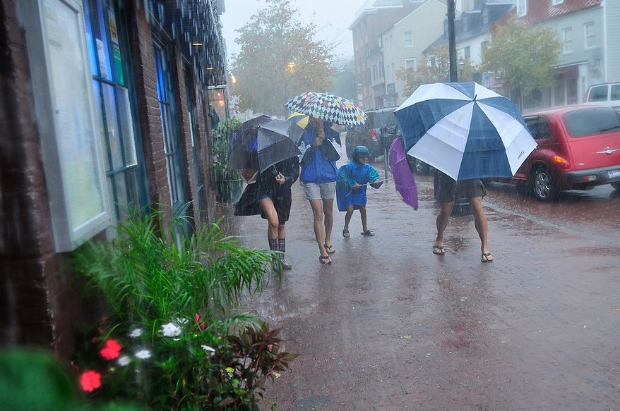 A family runs down Main Street as bands of high winds and heavy rain from Hurricane Irene lash Annapolis, Md., Saturday, August 27, 2011. (J.M. Eddins, Jr./The Washington Times)