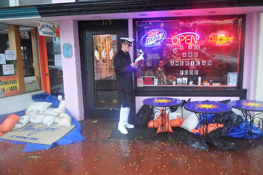 Midshipman 4th Class Devon Budzitowski, 18, a plebe at the United States Naval Academy, waits for a break in the bands of high winds and heavy rain from Hurricane Irene by reading a book under an awning in Annapolis, Md., Saturday, August 27, 2011. (J.M. Eddins, Jr./The Washington Times)