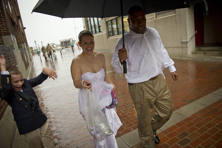 As Hurricane Irene makes her way up the Atlantic coast, newlyweds Sharon and Paul Branner, of Fairfax, Va., are joined by their ringer bearer Vaughn Messner , 9, (left) and flower girl Ryan Messner, 12, (right) as they are caught in the heavy downpour while leaving their wedding reception at the Charthouse at the waterfront in Alexandria, Va, Saturday, August 27, 2011. (Rod Lamkey Jr./The Washington Times)