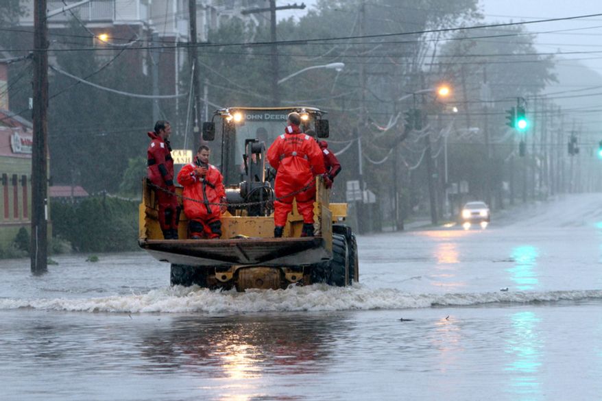 Village of Mamaroneck, N.Y. rescue swimmers ride on the front of a pay-loader en-route to their next mission during Hurricane Irene in Mamaroneck during Hurricane Irene Sunday, Aug. 28, 2011. ( AP Photo/The Journal News, Frank Becerra Jr)