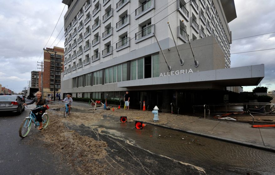 Bicyclists ride past the Allegria Hotel on West Broadway which was flooded from Hurricane Irene that swept through Long Island on Sunday, Aug. 28, 2011, in Long Beach, N.Y. (AP Photo/Kathy Kmonicek)