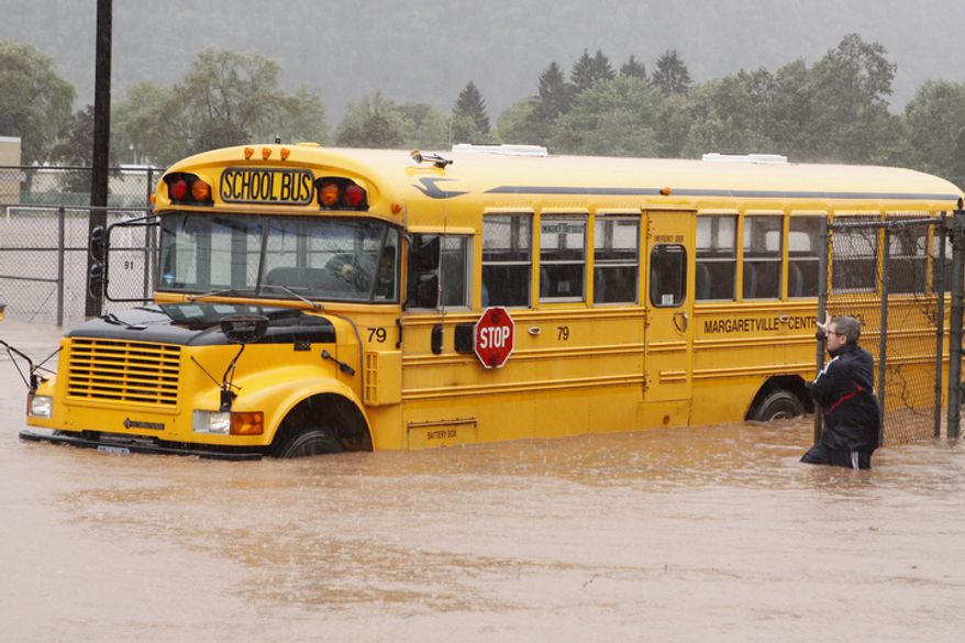 Margaretville Central School Athletic Director Jeremey Marks stands next to a school bus in floodwaters Sunday, Aug. 28, 2011, in Margaretville, N.Y.  (AP Photo/Dick Sanford)