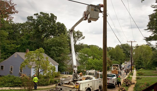 Workers with C.W. Wright Construction Company, a subcontractor for Pepco, work to secure a newly installed power line on Woodland Avenue in Takoma Park on Monday, while tree specialists with Arbor Care Inc. remove pieces of a large tree that knocked down the lines on this residential street. (Barbara L. Salisbury/The Washington Times)