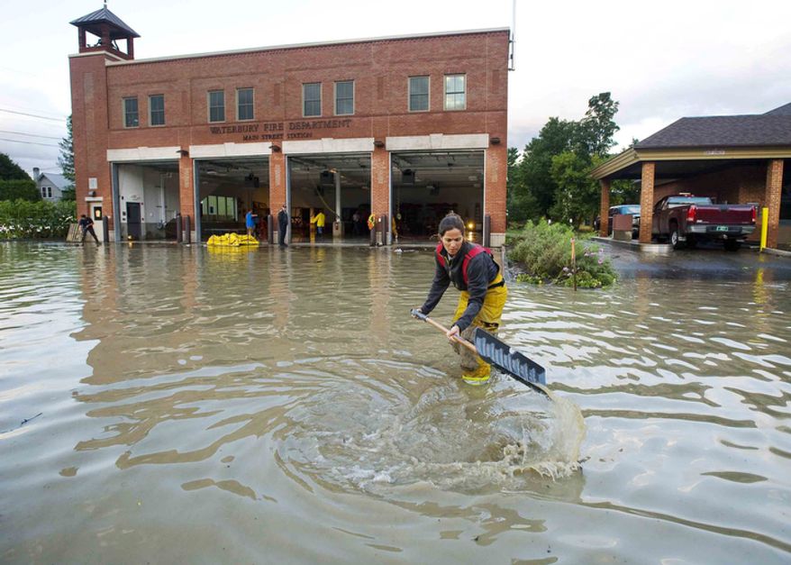 Firefighter Mandy Drake clears a storm drain in front of the fire department in Waterbury, Vt., in the wake of tropical storm Irene on Monday, August 29, 2011. The building was evacuated as high water from the Winooski River flooded downtown Sunday. (AP Photo/Burlington Free Press, Glenn Russell)