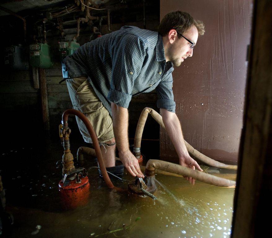 Matt Pelmear of Hoboken, N.J. adjusts the hose on one of four pumps he was using to remove several feet of water from the basement of the building he lives in Hoboken. (AP Photo/Joe Epstein)