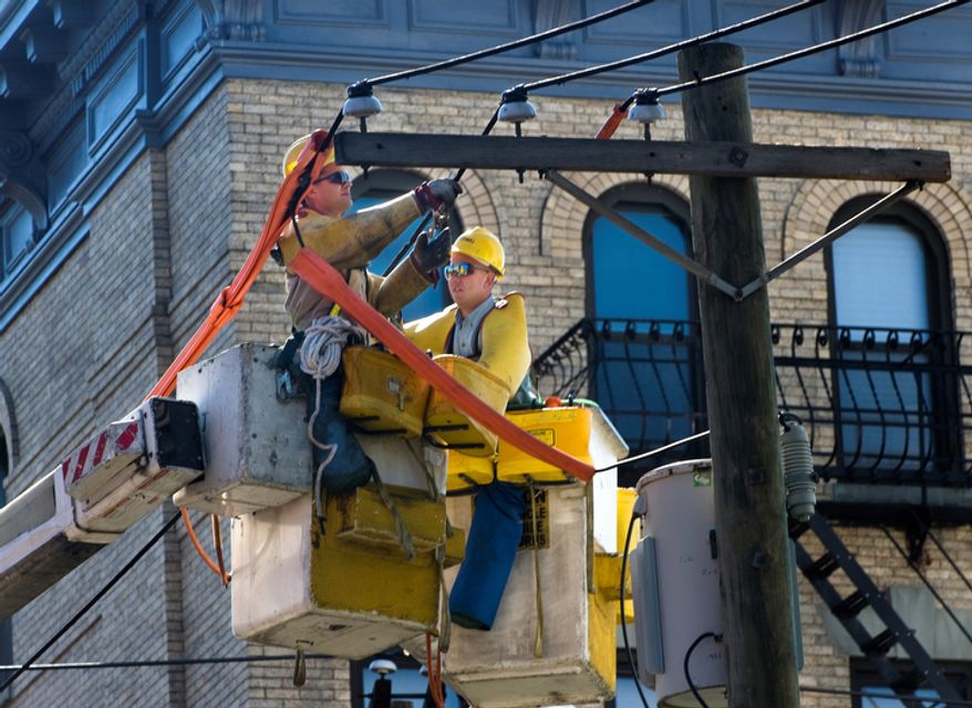 A crew from PSE&G puts a new power line from one utility pole to another at the intersection of Jefferson Street and 5th street as the clean up from Hurricane Irene continues, Monday Aug. 29, 2011 in Hoboken, N.J. (AP Photo/Joe Epstein)