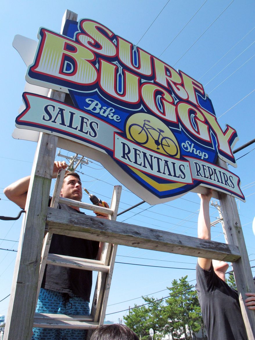 Doug Lawver, owner of a bicycle rental shop in Surf City, N.J., puts back a sign for his business on Monday that he removed ahead of the hurricane. (Associated Press)