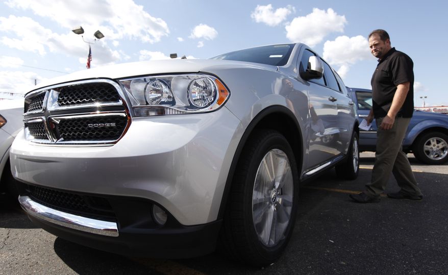 Jason Ashton checks out a new Dodge Durango at a dealership in Warren, Mich., on Thursday, Aug. 11, 2011. (AP Photo/Paul Sancya)