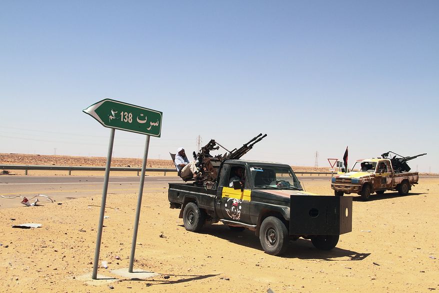 Libyan rebel vehicles with mounted missile launchers park next to a road sign that reads, in Arabic, "Sirte," on the front line, 86 miles from Sirte, Libya, on Monday, Aug. 29, 2011. Rebels have been converging from the east and west on Sirte, 250 miles east of Tripoli, preparing to battle forces loyal to Col. Moammar Gadhafi, whose tribe is based in the city. (AP Photo/Gaia Anderson)