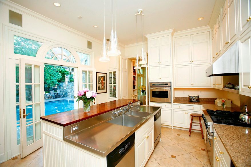 The kitchen has stone flooring, recessed and pendant lighting, granite counters, and a wood and stainless steel center island.