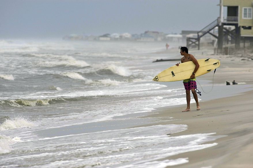 A surfer waits with his board to surf on Sept. 1, 2011, in Dauphin Island, Ala. (Associated Press/Mobile Press-Register)