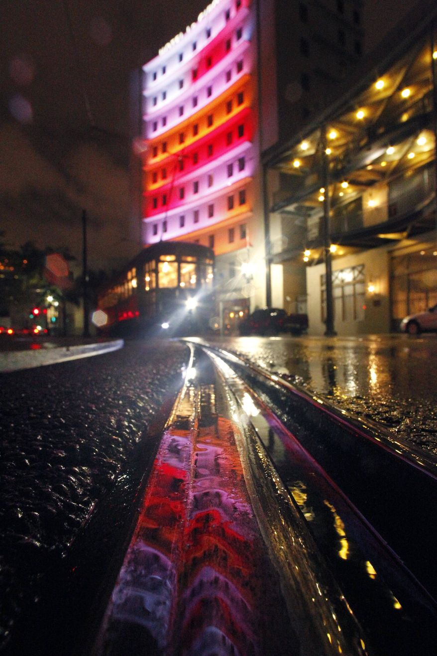 A hotel is reflected in puddles of rain from approaching Tropical Storm Lee at a streetcar track, as a streetcar passes through Lee Circle, in New Orleans, Friday, Sept. 2, 2011. Lee formed in the waters off Louisiana on Friday, threatening a drenching along much of the Gulf coast over the Labor Day weekend with up to 20 inches (50 centimeters) of rain in some spots. (AP Photo/Gerald Herbert)