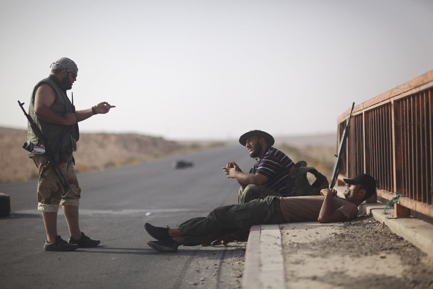Rebel fighters chat at a checkpoint between Tarhouna and Bani Walid, Libya, on Tuesday, Sept. 6, 2011. Col. Moammar Gadhafi is determined to fight his way back to power, the toppled dictator's spokesman said Tuesday, but a large convoy of his soldiers apparently has deserted, crossing the Libyan desert into neighboring Niger. (AP Photo/Alexandre Meneghini)
